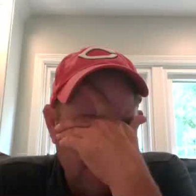 An Ample team member in a Reds cap covering his face with his hand on a video call